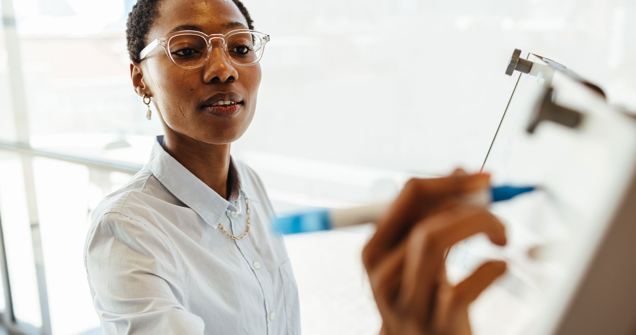 A close-up view of a woman wearing a white shirt writing notes.
